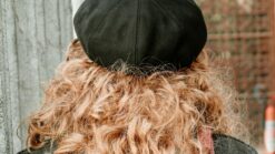 Cheveux bouclés blond cuivré sous un béret noir, vus de dos
